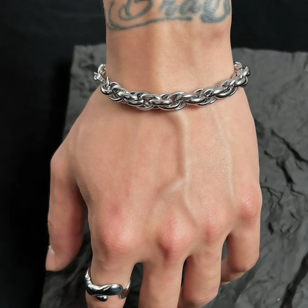 Hand wearing a silver chain bracelet on a dark textured background