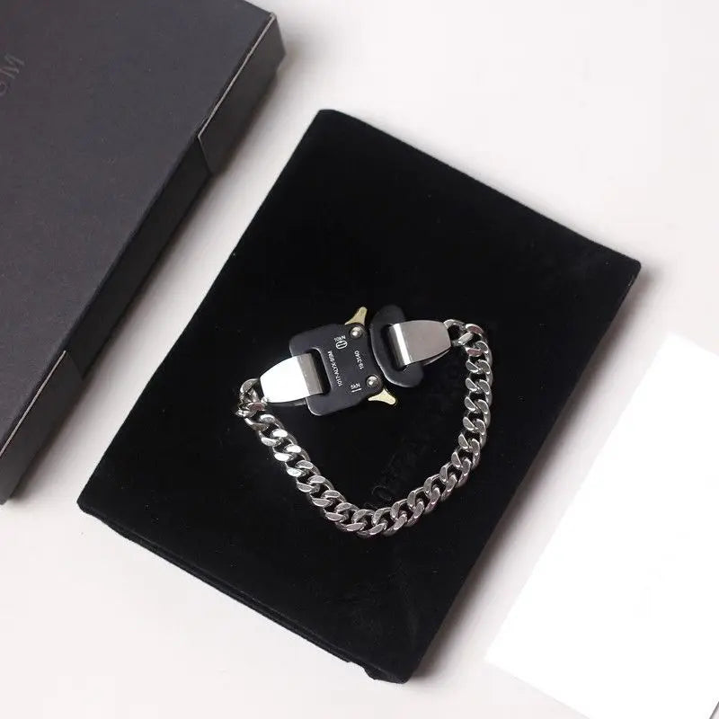Black and silver chain bracelet on a black velvet cushion with a white background